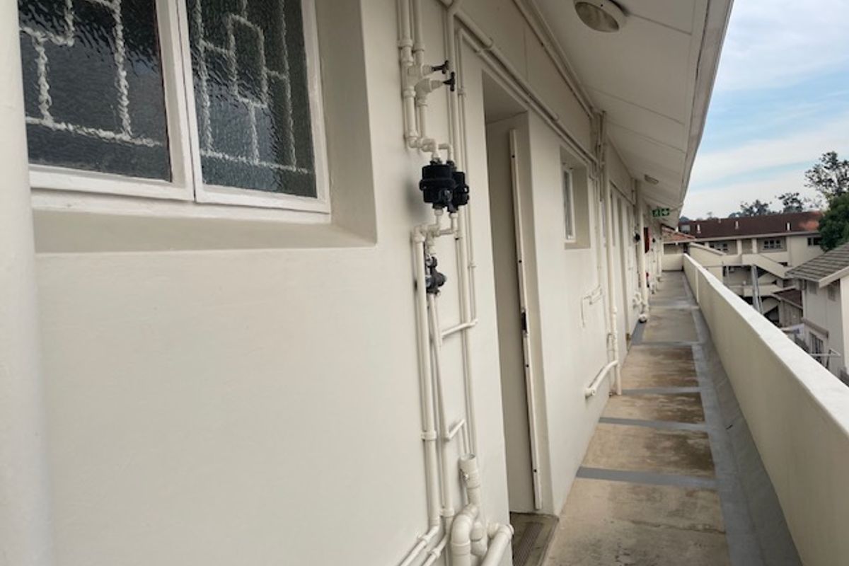 Exterior walkway providing access to office units, featuring exposed plumbing infrastructure and a concrete balcony floor.