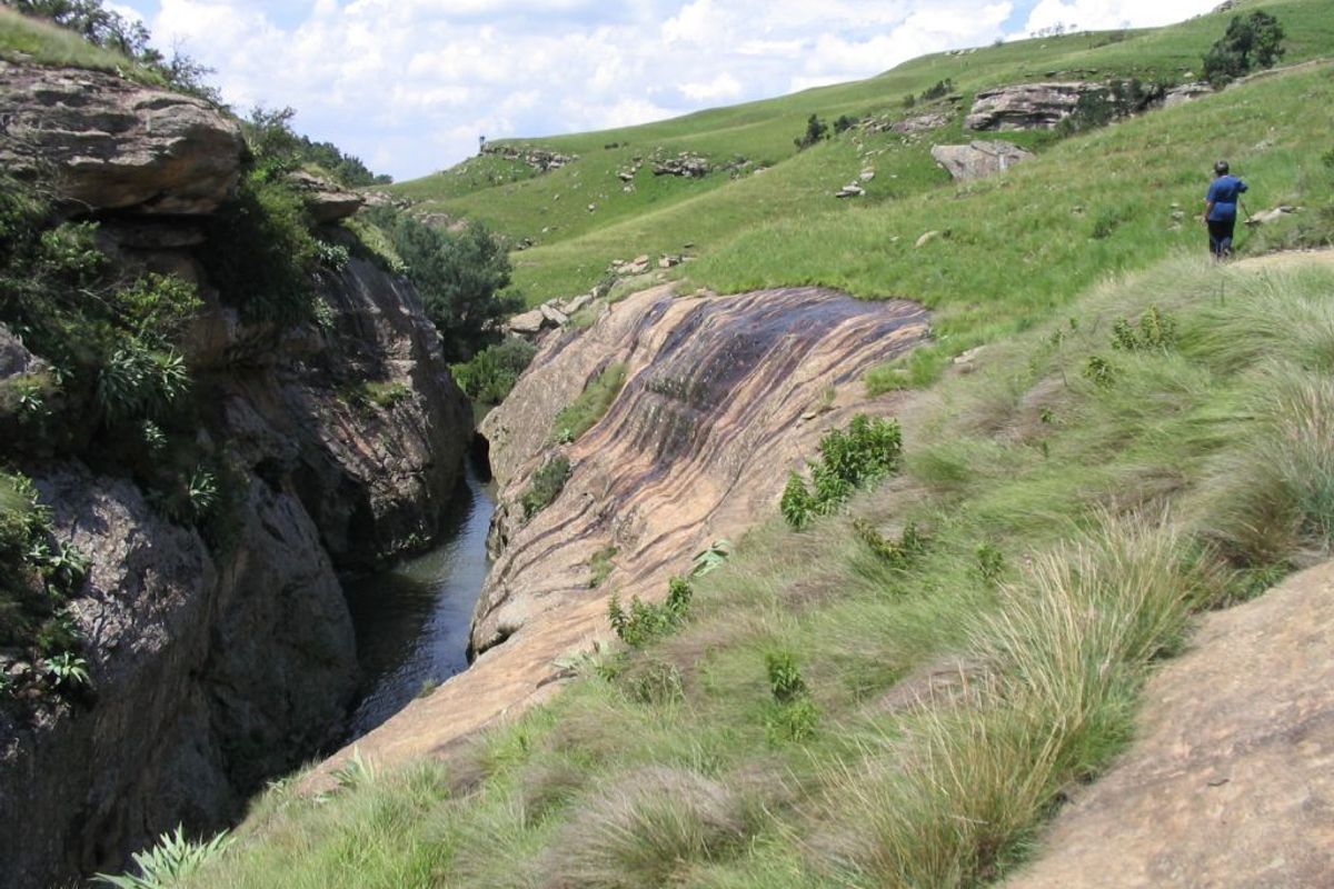 A scenic view of a natural stream flowing through a rocky gorge within the farm landscape.