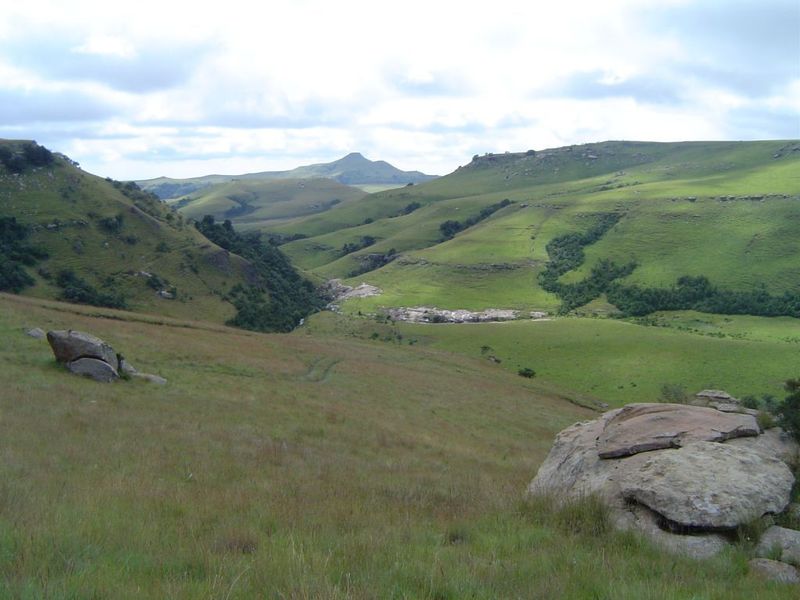 A scenic landscape view of rolling green hills and rocky terrain on the farm property.