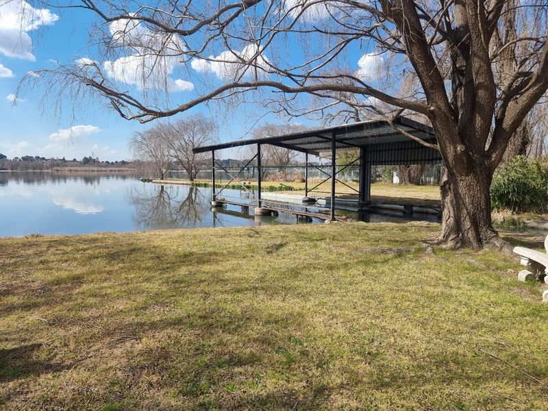 A waterfront property featuring a metal boat house structure situated on the edge of a lake, offering direct water access.