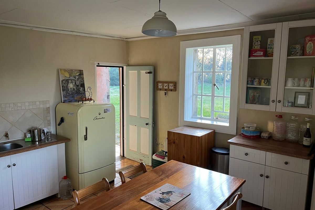 A rustic farmhouse kitchen featuring built-in cabinetry, wooden countertops, a stainless steel sink, and direct access to the garden through a side door.