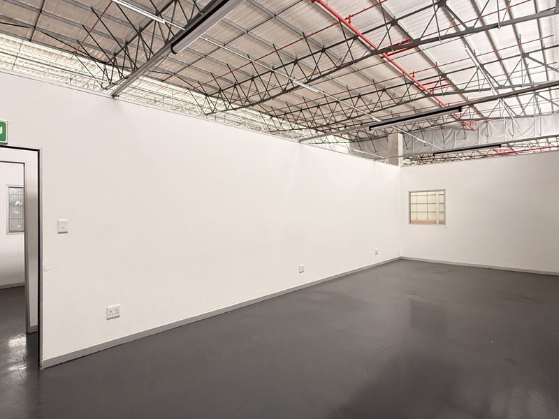 A clean, open-plan industrial utility space featuring exposed steel roof trusses, fire sprinkler systems, and durable epoxy flooring.