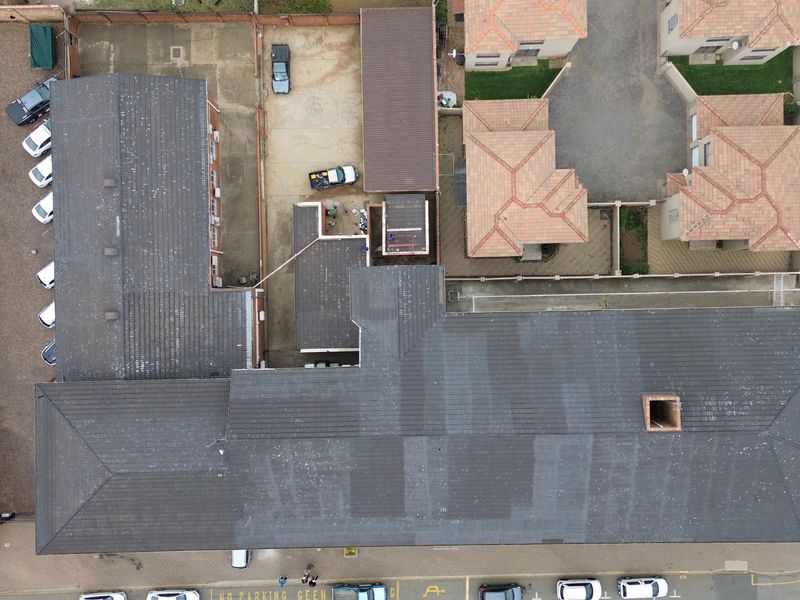 Aerial view of the office property showing the main building roof, covered parking bays, and paved exterior grounds.