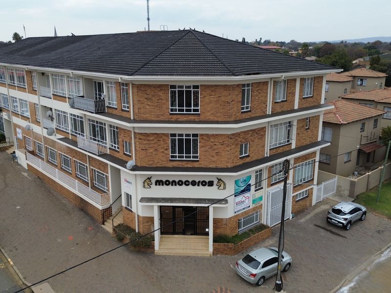 Aerial view of a multi-story commercial office building featuring face brick construction, a tiled roof, and dedicated paved parking facilities.