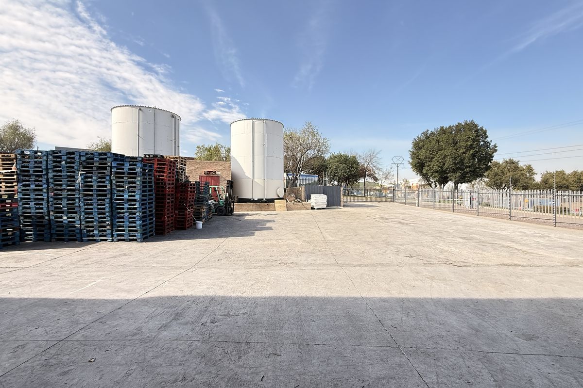 Spacious industrial yard featuring concrete hardstand, perimeter fencing, and large storage silos, suitable for logistics or manufacturing operations.