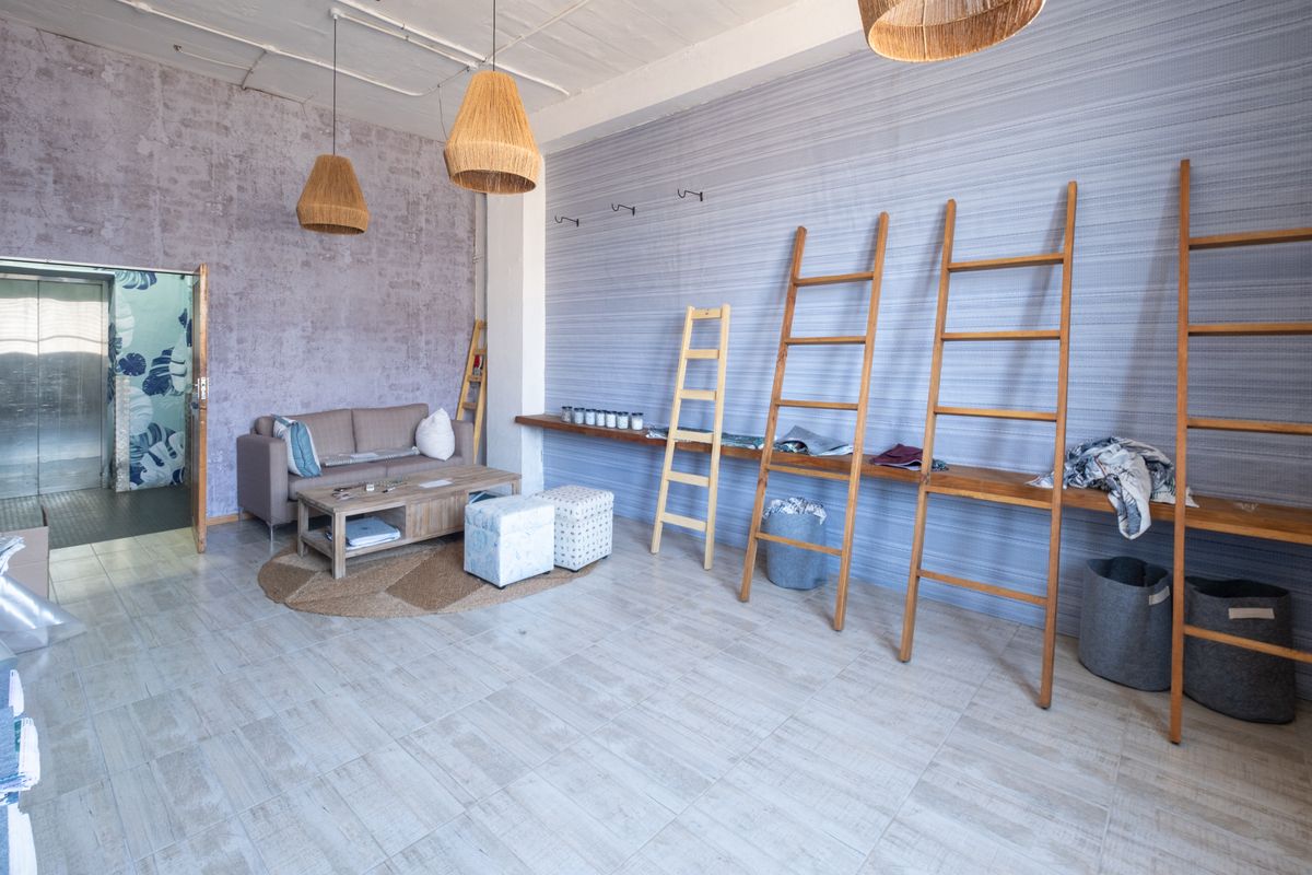 A spacious industrial-style room featuring tiled flooring, textured feature walls, and high ceilings with exposed structural elements.