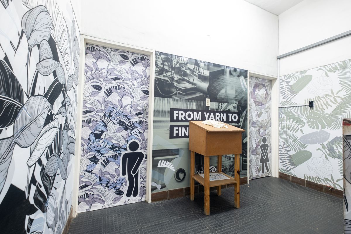 A functional industrial restroom area featuring patterned wall coverings and designated male and female access doors.