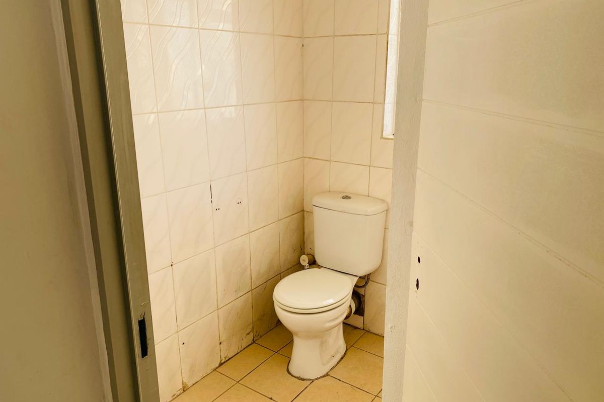A compact, functional restroom featuring a standard white toilet, tiled walls, and tiled flooring.