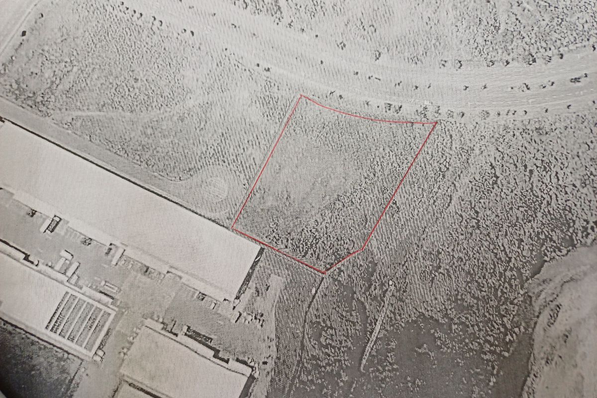 Aerial view of a vacant commercial land plot with red boundary lines indicating the property perimeter.