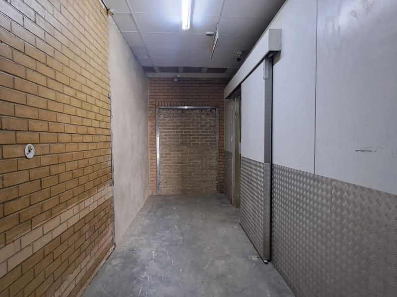 Industrial hallway featuring exposed brickwork, checker plate wall cladding, and a sliding industrial door, suitable for warehouse or commercial storage access.