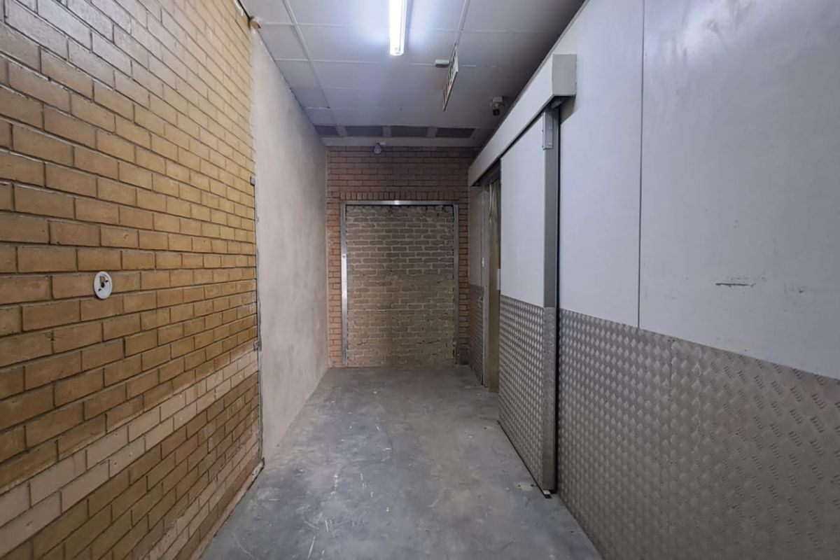 Industrial hallway featuring exposed brickwork, checker plate wall cladding, and a sliding industrial door, suitable for warehouse or commercial storage access.