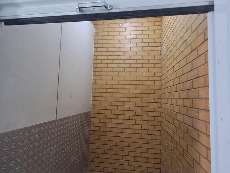 A clean utility or storage space featuring exposed brick walls and durable metal checker plate wall cladding, suitable for industrial or workshop use.