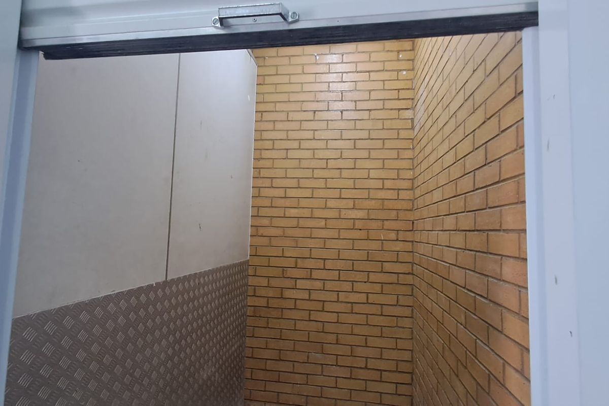 A clean utility or storage space featuring exposed brick walls and durable metal checker plate wall cladding, suitable for industrial or workshop use.