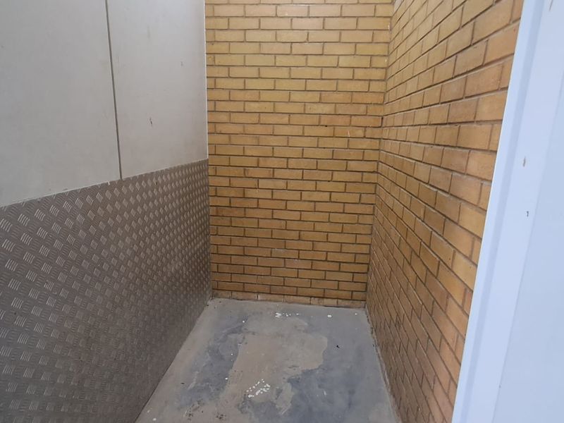 A functional utility storage space featuring exposed brick walls, durable checker plate metal cladding, and a concrete floor.