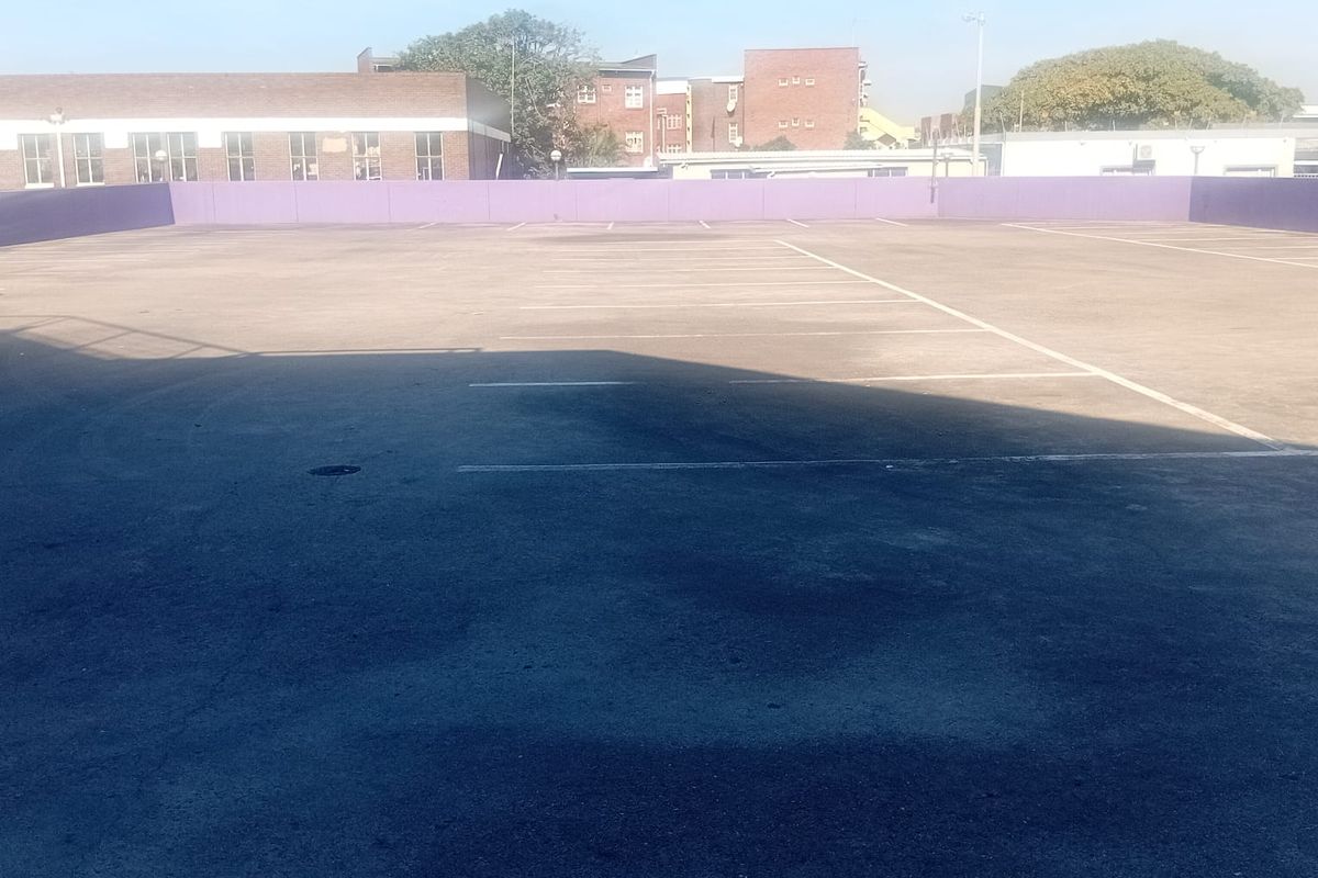 An open-air rooftop parking area featuring marked bays and a perimeter wall, providing ample space for commercial vehicle parking.