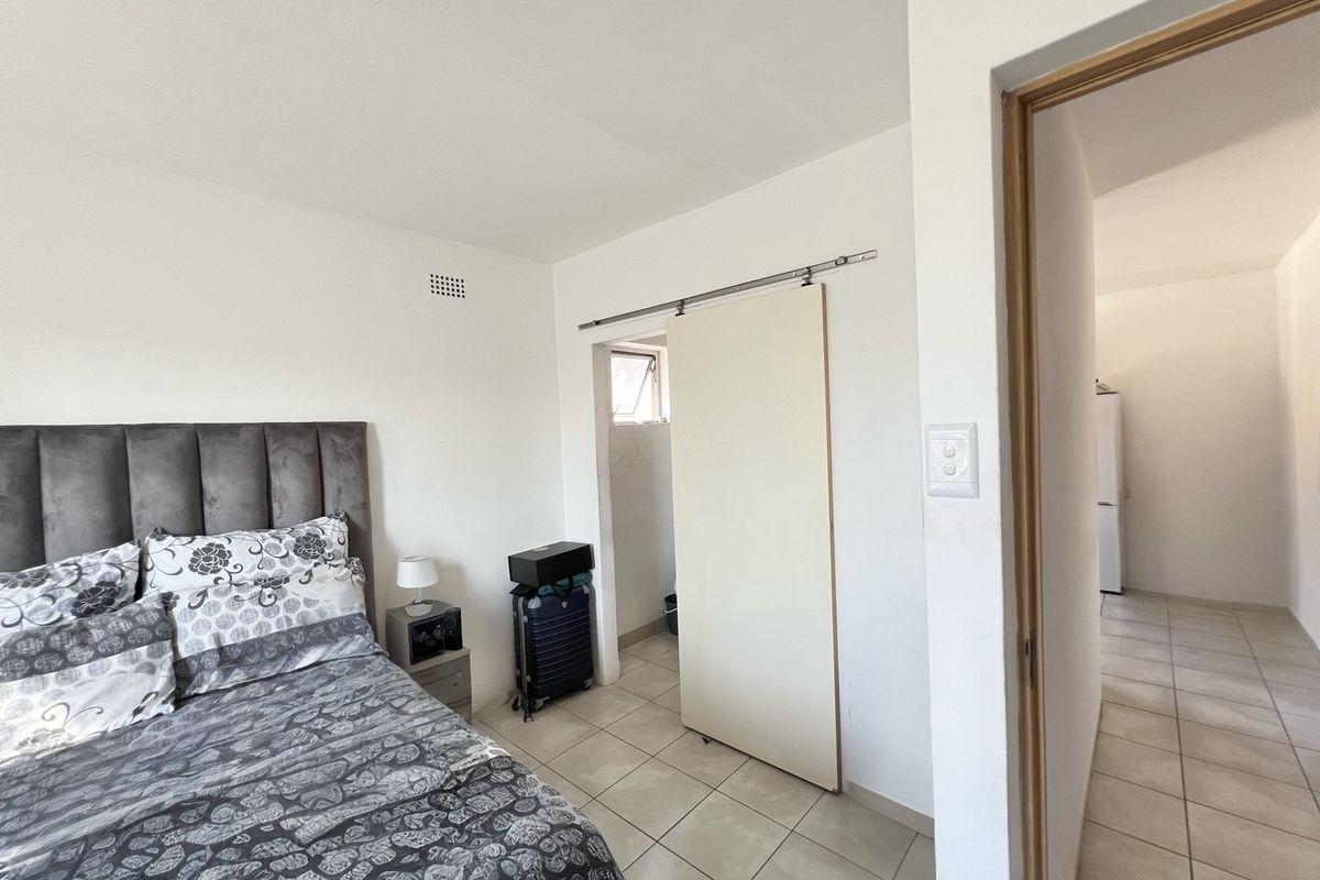 Bedroom featuring tiled flooring, a sliding door leading to an en-suite, and direct access to an adjacent hallway.