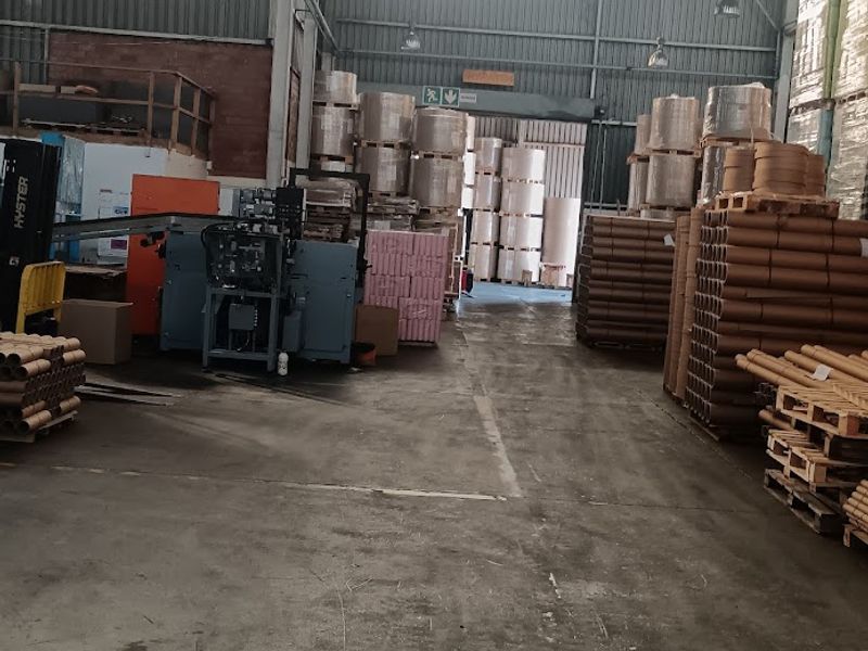 Spacious industrial warehouse facility featuring high ceilings with exposed steel trusses, concrete flooring, and large sliding access doors for logistics operations.