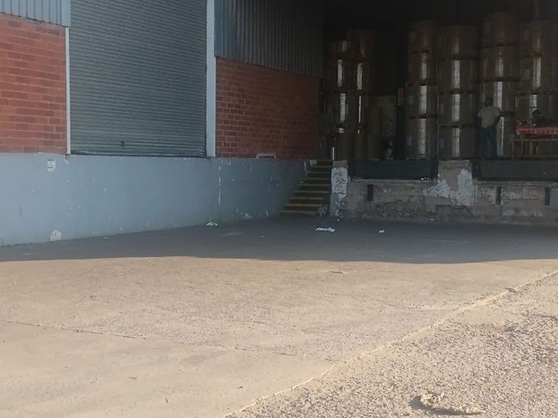 Industrial loading bay area featuring a roller shutter door, concrete apron, and raised loading dock with visible wear to the masonry and finishes.