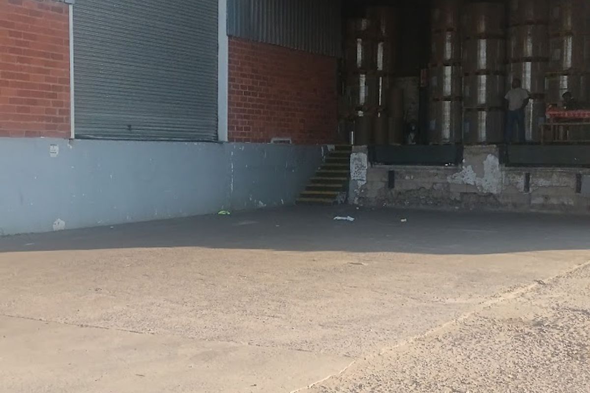Industrial loading bay area featuring a roller shutter door, concrete apron, and raised loading dock with visible wear to the masonry and finishes.