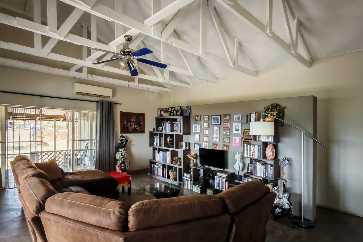 Spacious living room featuring high vaulted ceilings with exposed white trusses, a ceiling fan, and large sliding glass doors leading to the patio.