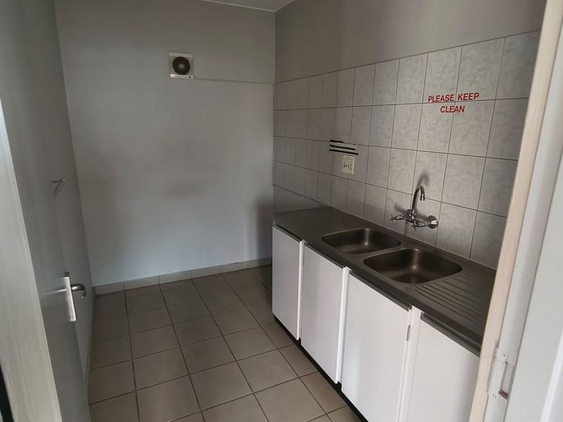 A functional scullery area featuring a double stainless steel sink, built-in cabinetry, tiled splashback, and an extractor fan.