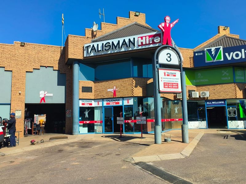 Front elevation of a commercial retail property featuring brick construction, glass storefronts, and prominent signage for Talisman Hire and Voltex.