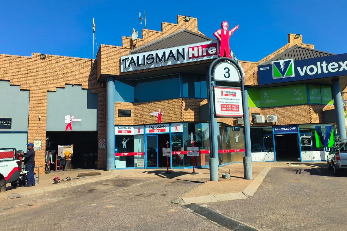 Front exterior view of a commercial retail building featuring brick construction, glass storefronts, and prominent signage for multiple tenants.