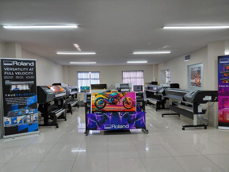 A well-lit commercial office space currently utilized as a showroom for large-format printing equipment with polished tiled flooring.