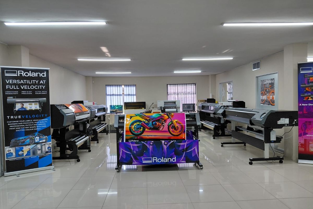 A well-lit commercial office space currently utilized as a showroom for large-format printing equipment with polished tiled flooring.