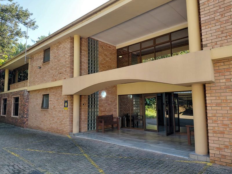 Front exterior view of a two-story office building featuring a brick facade, covered entrance, and paved parking area.