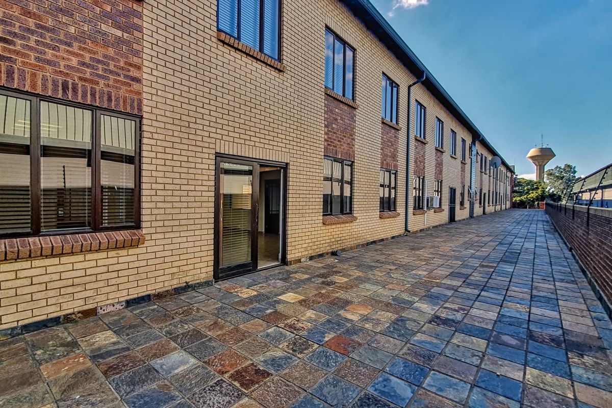 Exterior view of the office building featuring a paved walkway, brick facade, and multiple window access points.