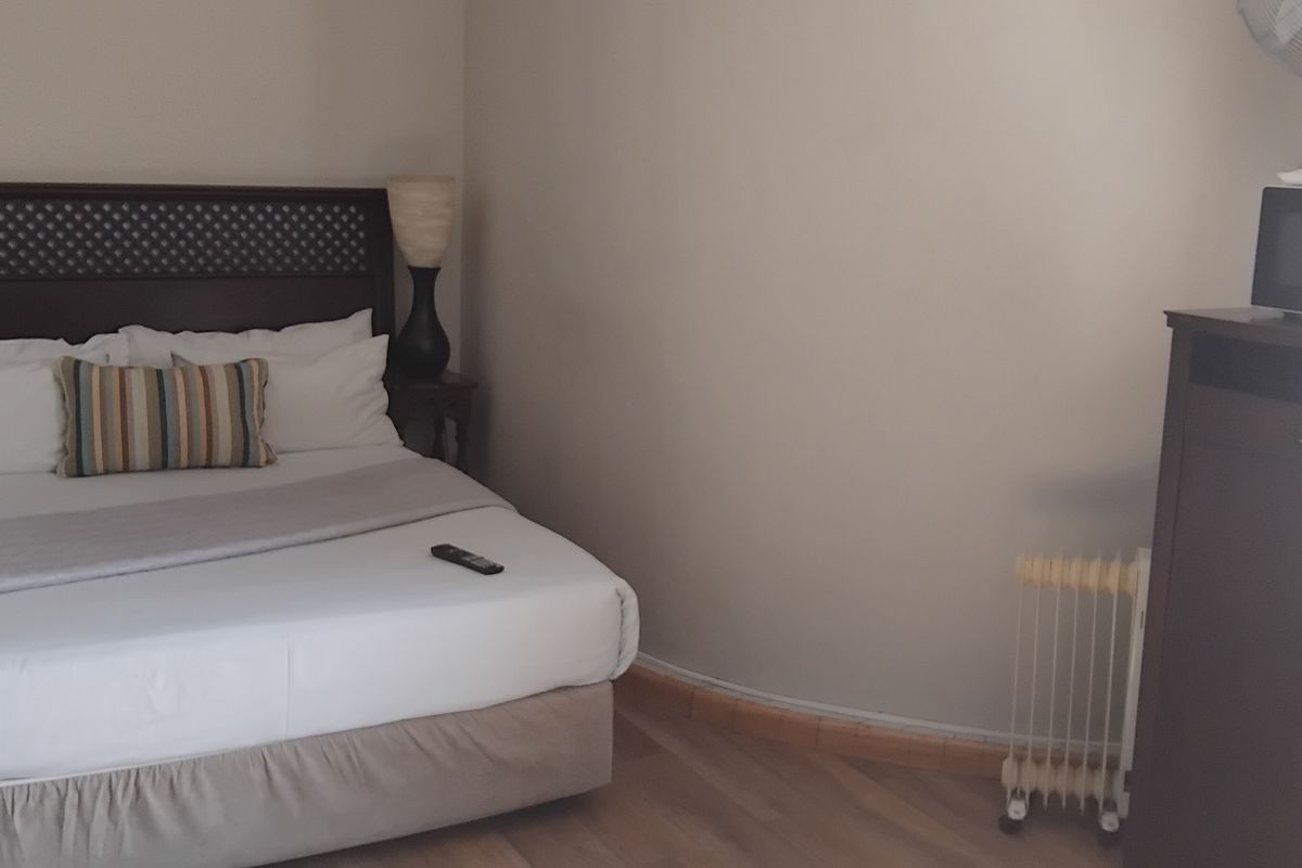 A bedroom featuring laminate flooring and a curved wall design, providing a functional space for guests.