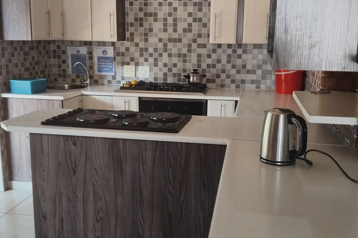 A functional kitchen featuring dual hobs, built-in oven, mosaic tile backsplash, and ample cabinetry with laminate countertops.