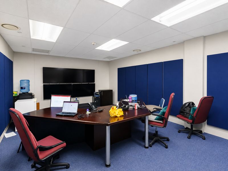 A functional office space featuring acoustic wall panels, suspended ceiling with recessed lighting, and carpeted flooring.