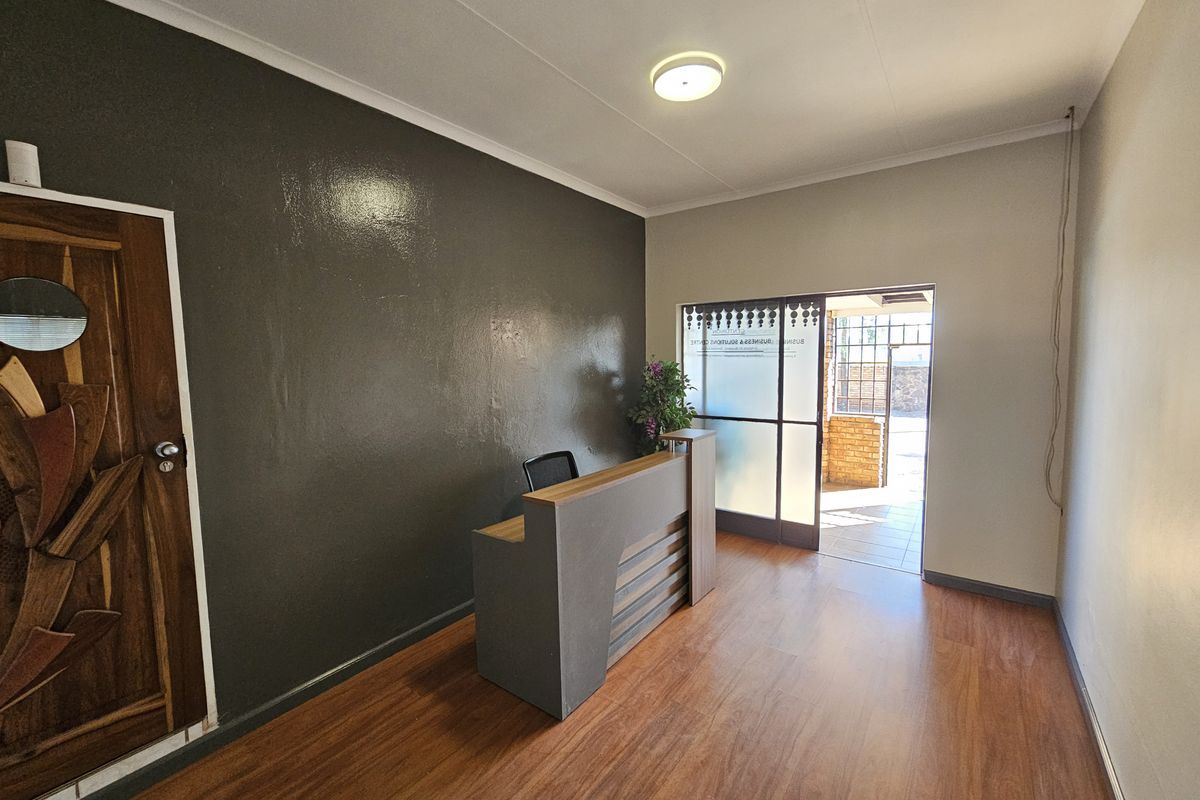 A professional office entry area featuring laminate flooring, a built-in reception desk, and a glass sliding door leading to an outdoor space.