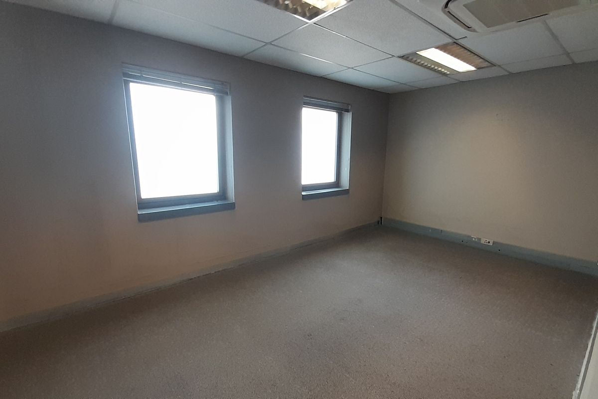 A vacant office space featuring neutral walls, carpeted flooring, and a suspended ceiling with integrated lighting.