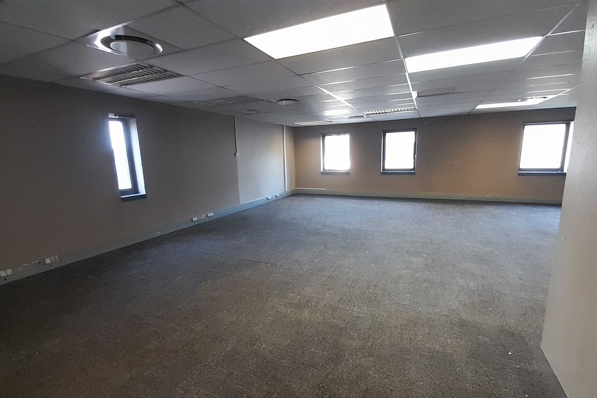 A spacious, empty open-plan office area featuring a suspended ceiling, recessed lighting, and carpeted flooring, ready for custom fit-out.