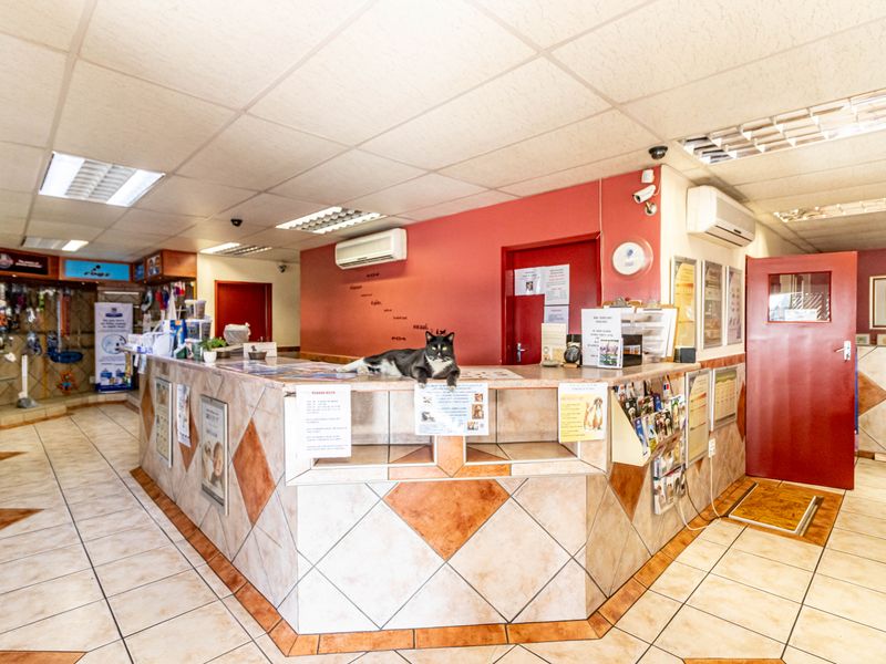 A functional office reception area featuring a built-in service counter, tiled flooring, and integrated air conditioning units.