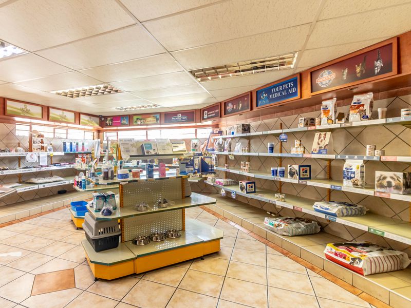 A commercial retail office space featuring tiled flooring, suspended ceilings with recessed lighting, and extensive built-in wall shelving for product display.
