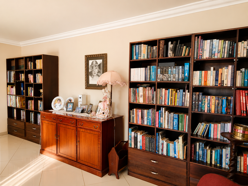 A well-maintained living area featuring extensive built-in wooden bookshelves, elegant crown molding, and polished tiled flooring.
