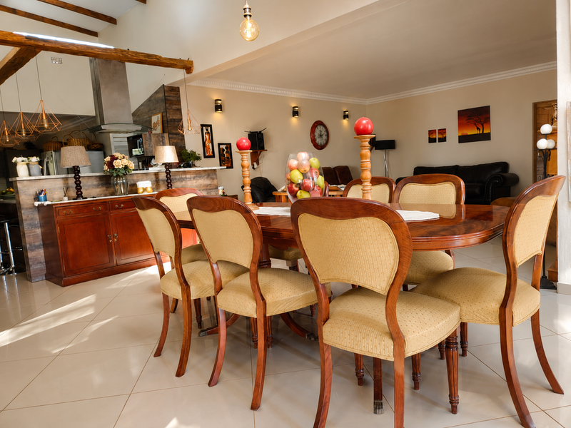 Spacious open-plan dining and kitchen area featuring exposed timber beams, tiled flooring, and a functional kitchen layout with a stainless steel extractor fan.