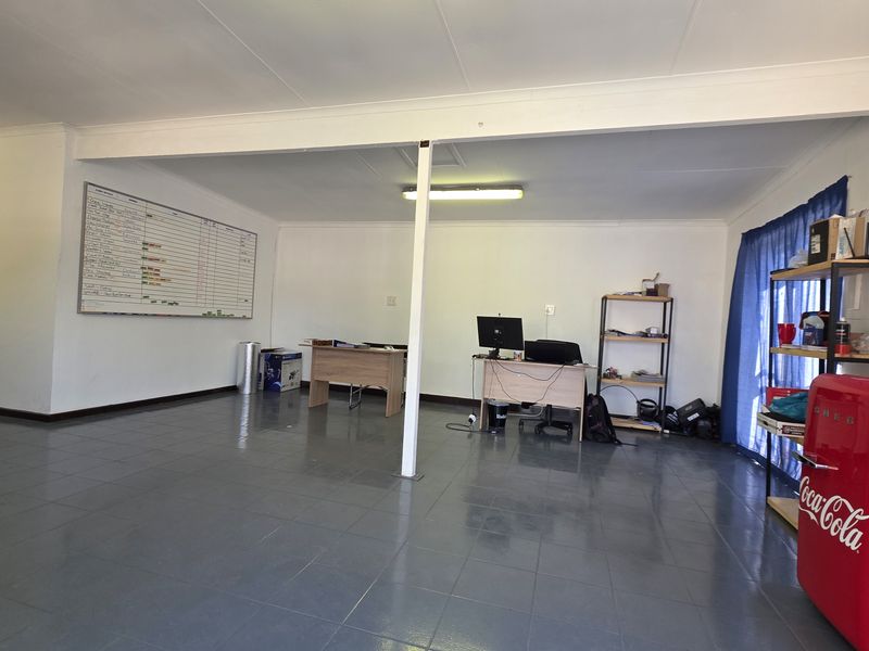 A functional office space featuring tiled flooring, a central support column, and overhead fluorescent lighting, suitable for a professional work environment.