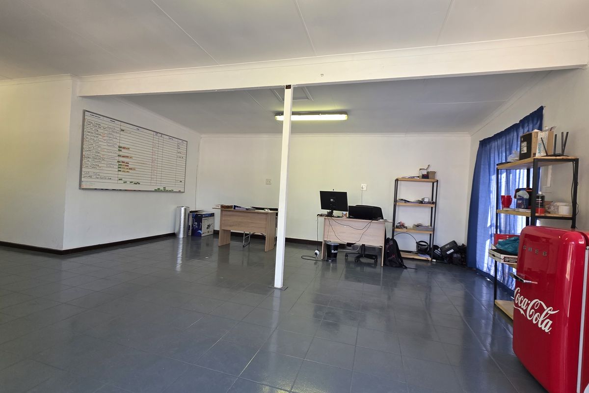 A functional office space featuring tiled flooring, a central support column, and overhead fluorescent lighting, suitable for a professional work environment.
