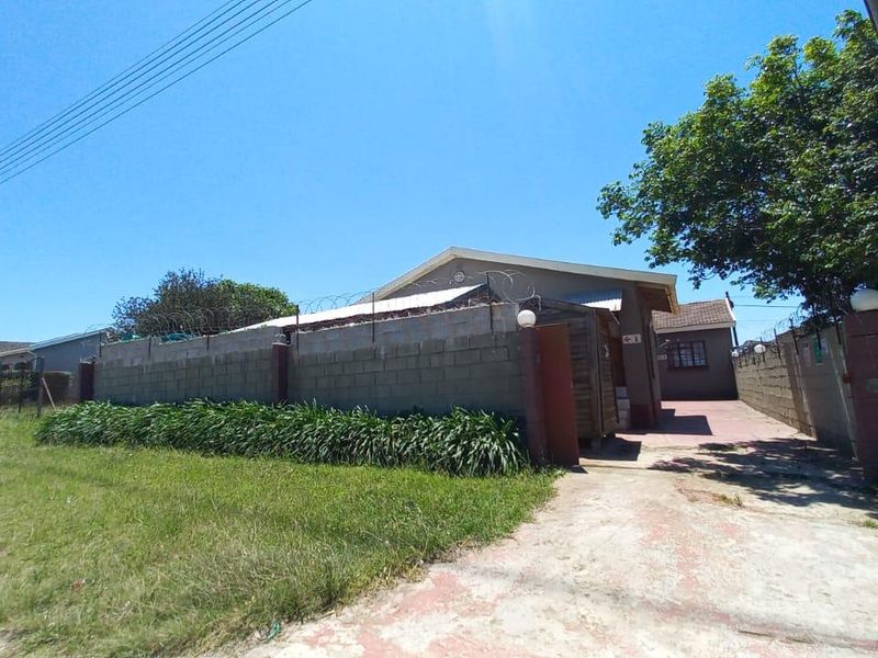 Front exterior view of the property featuring a concrete driveway, gated entrance, and a secure boundary wall topped with razor wire.