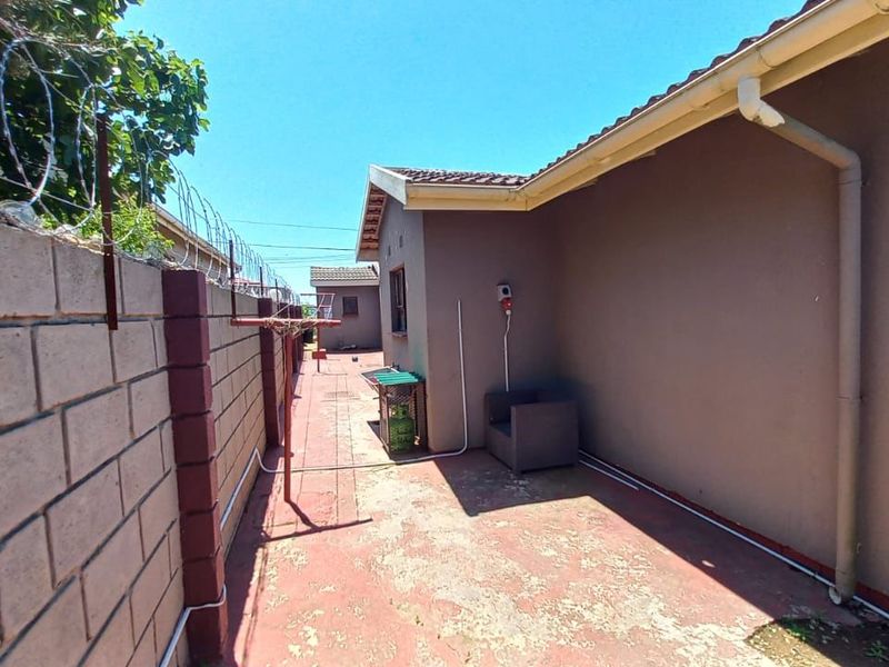 A side exterior walkway featuring a perimeter wall with razor wire, tiled roofing, and paved flooring along the side of the building.
