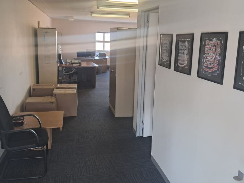 A functional office space featuring carpeted flooring and overhead fluorescent lighting, suitable for a professional work environment.