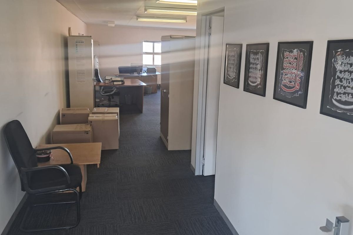 A functional office space featuring carpeted flooring and overhead fluorescent lighting, suitable for a professional work environment.