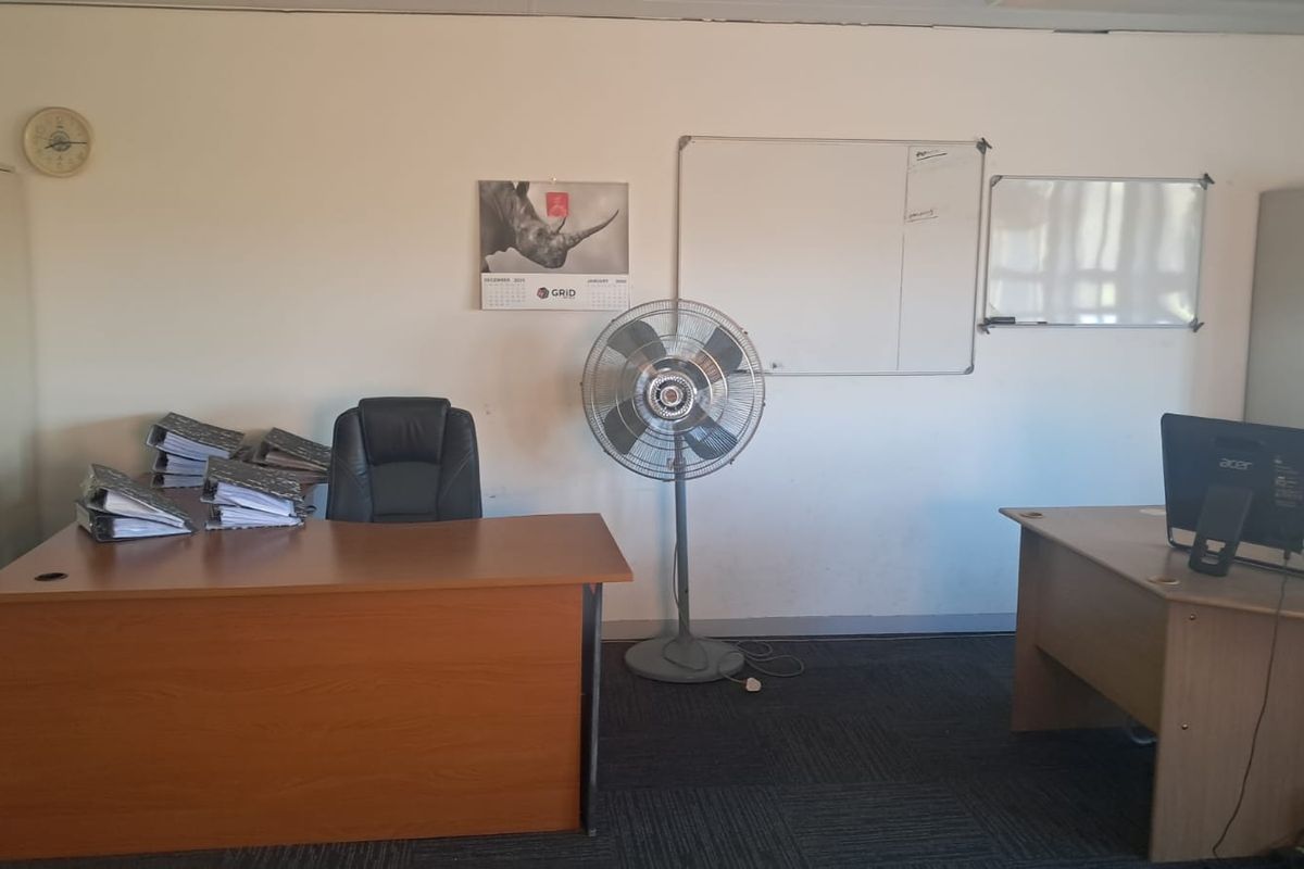 A functional office space featuring carpeted flooring, built-in storage cabinets, and wall-mounted whiteboards, suitable for a professional work environment.