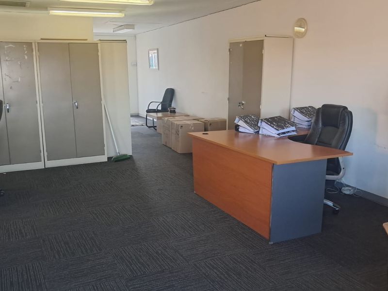 A functional office space featuring built-in storage cupboards, carpeted flooring, and overhead fluorescent lighting, suitable for a professional work environment.
