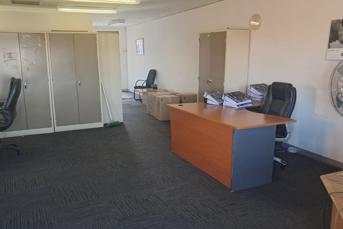A functional office space featuring built-in storage cupboards, carpeted flooring, and overhead fluorescent lighting, suitable for a professional work environment.